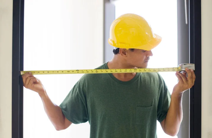 Person mit Helm und Zollstock